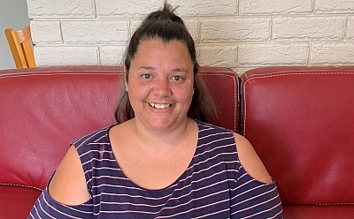 Carissa sitting on the red couch and holding a cup of coffee