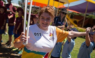 Lenny running with the Commonwealth Games Baton giving high fives to children along the way